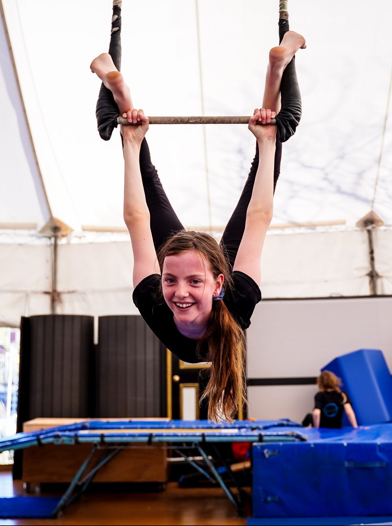 A girl hangs upside down from a trapeze